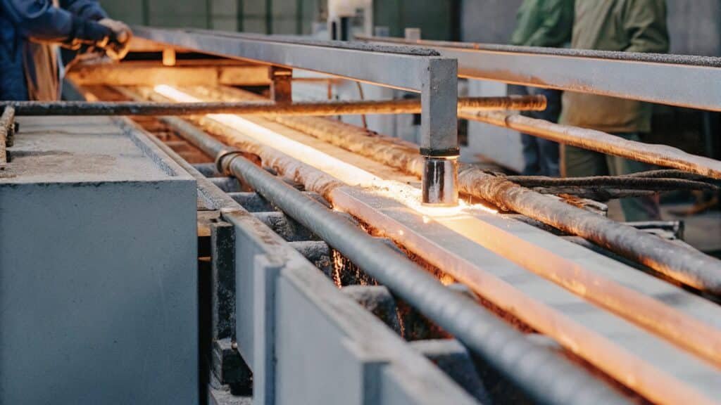 An animated diagram showing a heated aluminum billet being pushed through an extrusion die to form a long tube.